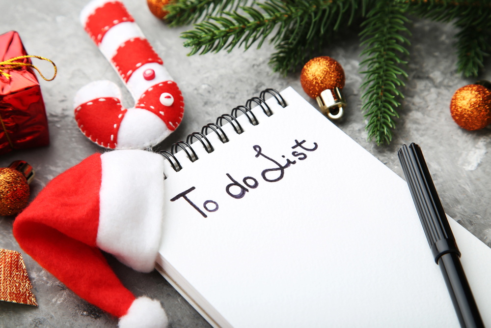 Spiral notepad on snow with the words To do list. With Holiday pines, ornaments and a little stocking hat nearby.